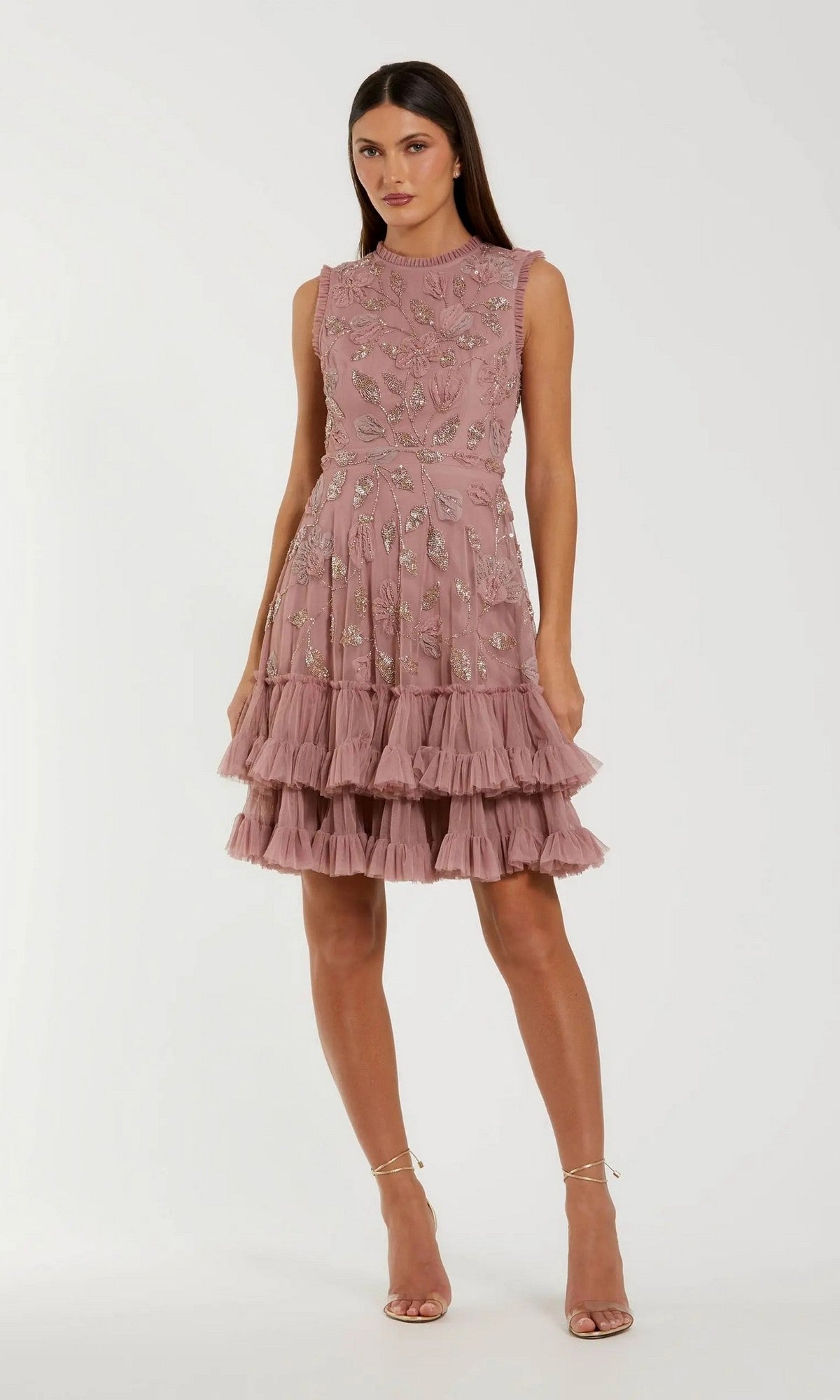 A woman wearing the Mac Duggal 9403 short party dress in Antique Rose—a sleeveless, knee-length fit and flare style featuring ruffle layers and floral embroidery—stands against a plain background.
